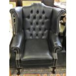 A black leather button back wing armchair