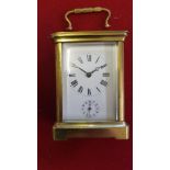 A brass alarm carriage clock, the white enamel dial with subsidiary alarm dial, the movement