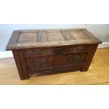 An 18th century and later oak coffer, with panelled lid and carved front panels, 107 x 47 x 50 cm.