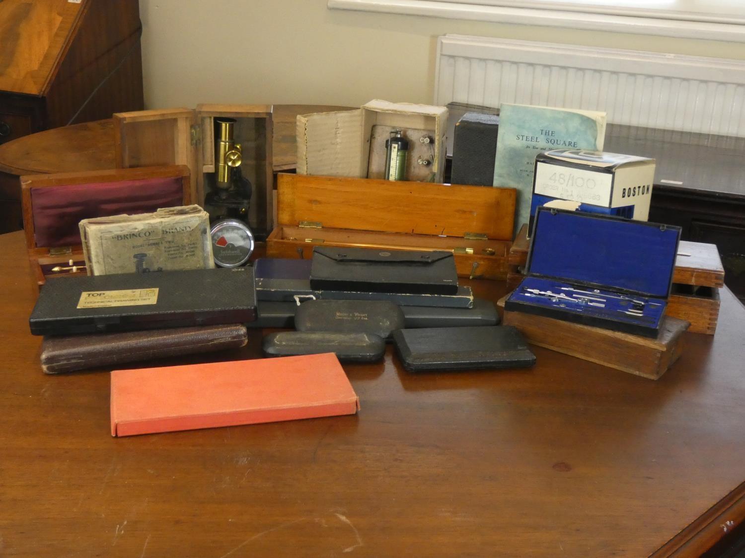 A collection of technical drawing instruments including slide rulers, a cased tachometer, cased