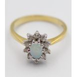 An 18ct gold opal and diamond cluster ring, claw set with an oval stone, bordered by 10