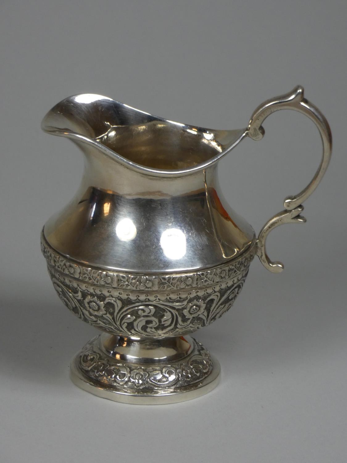 An Indian silver cream jug, indistinctly marked, of baluster form, with chased floral decoration, - Image 2 of 3