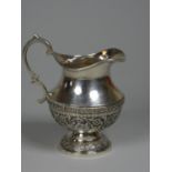 An Indian silver cream jug, indistinctly marked, of baluster form, with chased floral decoration,
