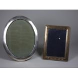 An oval silver photograph frame, Birmingham 1916, 24 x 19 cm and another London 2000, Millennium