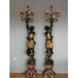 A pair of painted wood Blackamoor standard lamps, in black and gold, supporting seven light