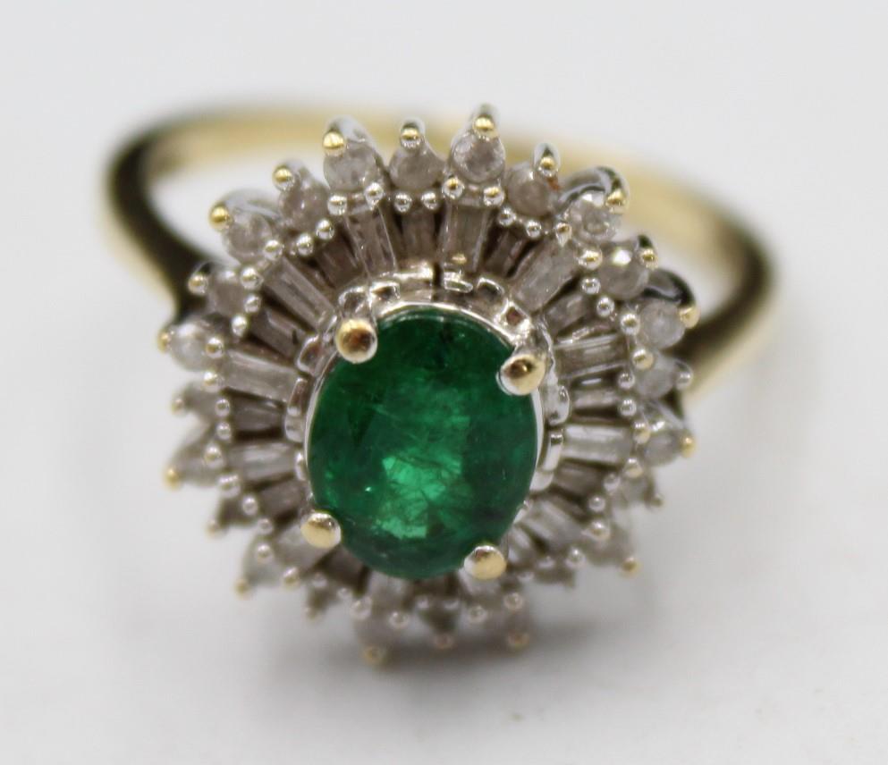 A 9ct gold emerald and diamond cluster ring, the claw set oval stone bordered by baguette and