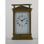 A French brass carriage time piece, with arched pediment, the white enamel dial unsigned, the