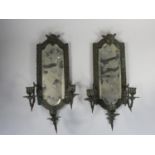 A pair of bronzed metal wall sconces, with bevelled glass mirrors, the three scones with mask bases,