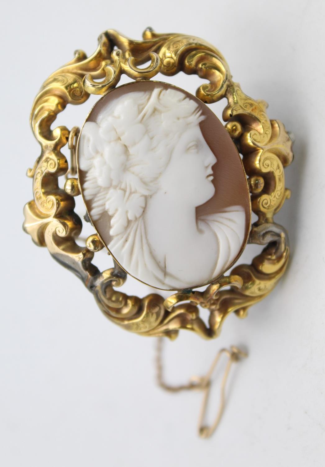 A Victorian gold mounted shell cameo brooch, depicting a Bacchanalian lady, scroll mount, 5 x 4 cm.