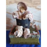 An early 20th Century antique style musical automaton, in the form of a macabre baby doll in basket;