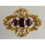 A Victorian gold and garnet brooch, set with three graduated mixed cut stones within an openwork