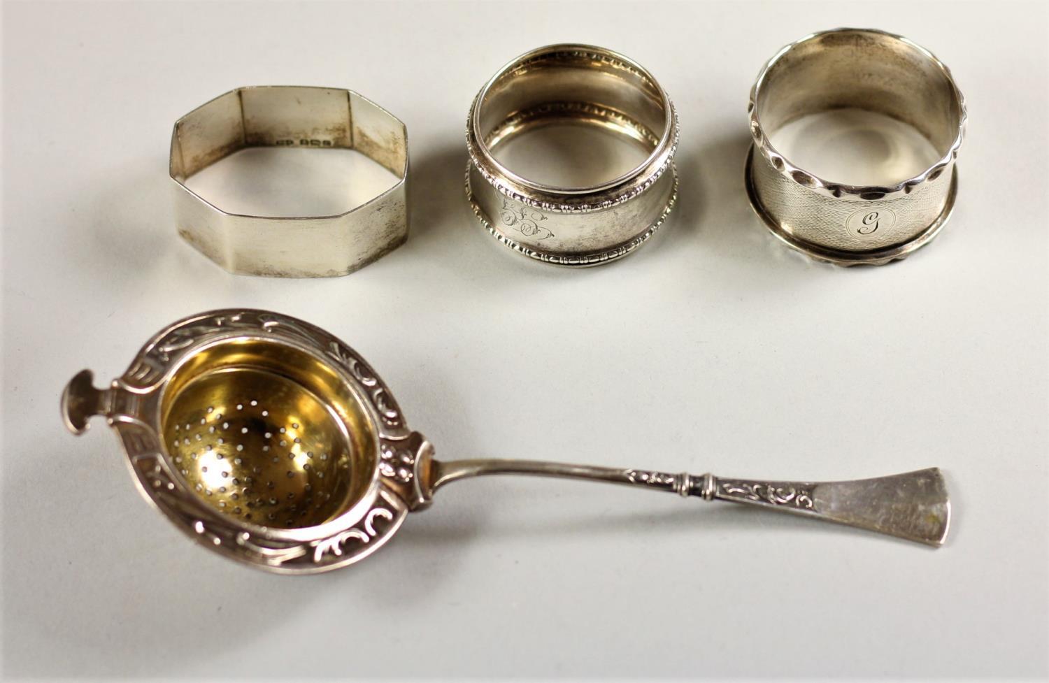 A Continental 800 standard silver tea strainer and three English silver napkin rings, 2.5 oz (4).