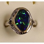 An 18ct white gold Queensland black boulder opal and diamond ring, collet set with an irregular