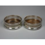 A pair of silver bottle coasters, London 1984, with pierced border and turned mahogany base,