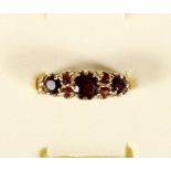A 9ct gold garnet three stone ring with points between, 2.1gm, Q 1/2