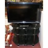 A Panasonic 32 inch LCD TV, model TX 10 BA, together with a smoked glass TV/Hi-Fi stand and remote.