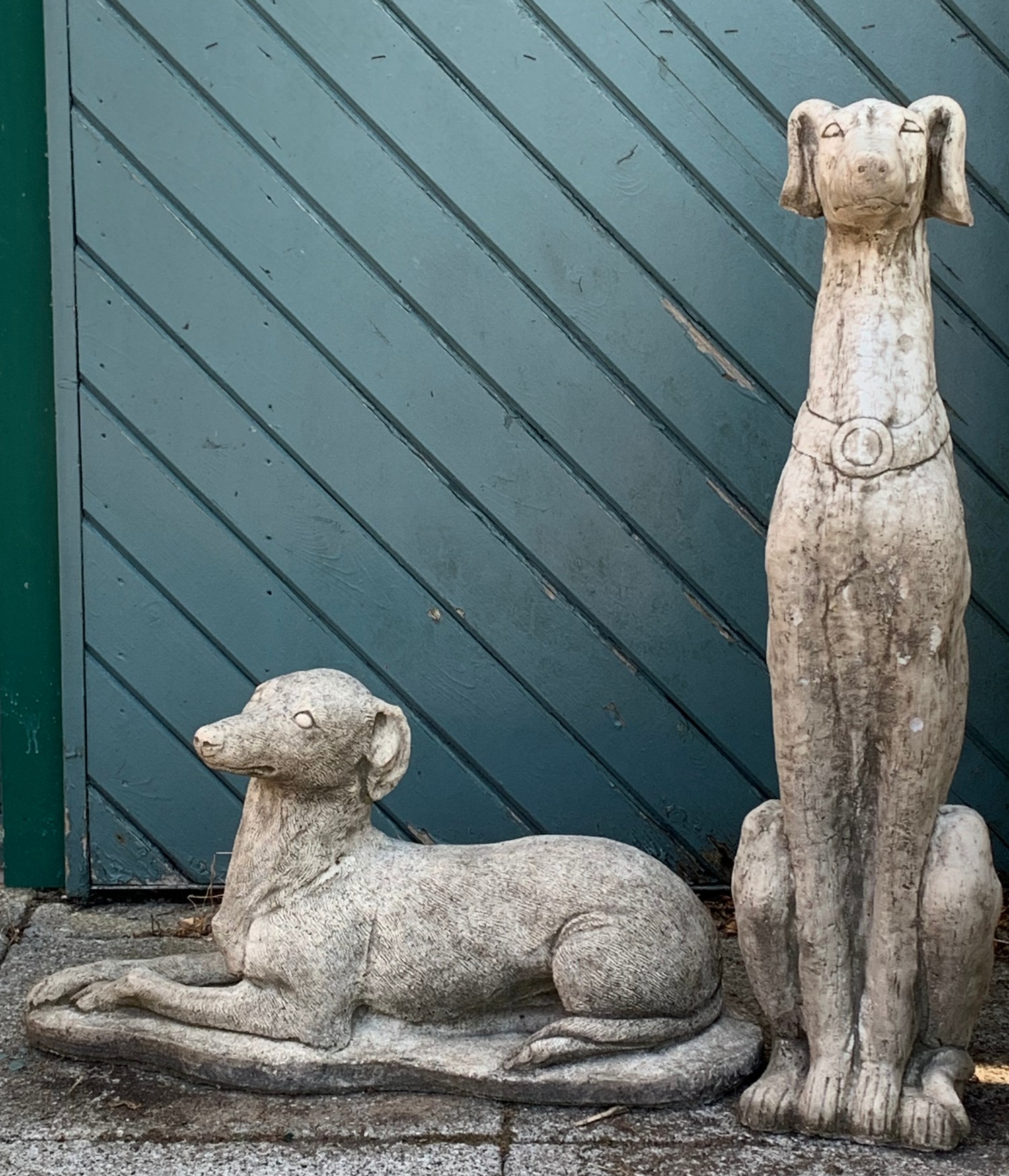 A composite garden figure depicting a seated greyhound / whippet, together with a similar