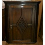 A late 19th early 20th Century carved oak corner cabinet. The four panel fielded feature door, opens