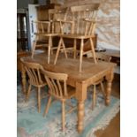 A stripped pine dining table with drawer to one end, together with a set of six pine chairs. (two