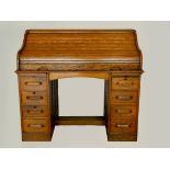 An Edwardian oak roll-top pedestal desk, the tambour top opening to reveal a fitted interior, four