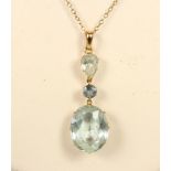 An aquamarine negligee pendant, the claw set oval mixed cut stone, 18 x 14 x 8mm, with a blue zircon