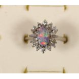 An 18ct white gold black opal doublet and diamond cluster ring, London 1973, claw set with