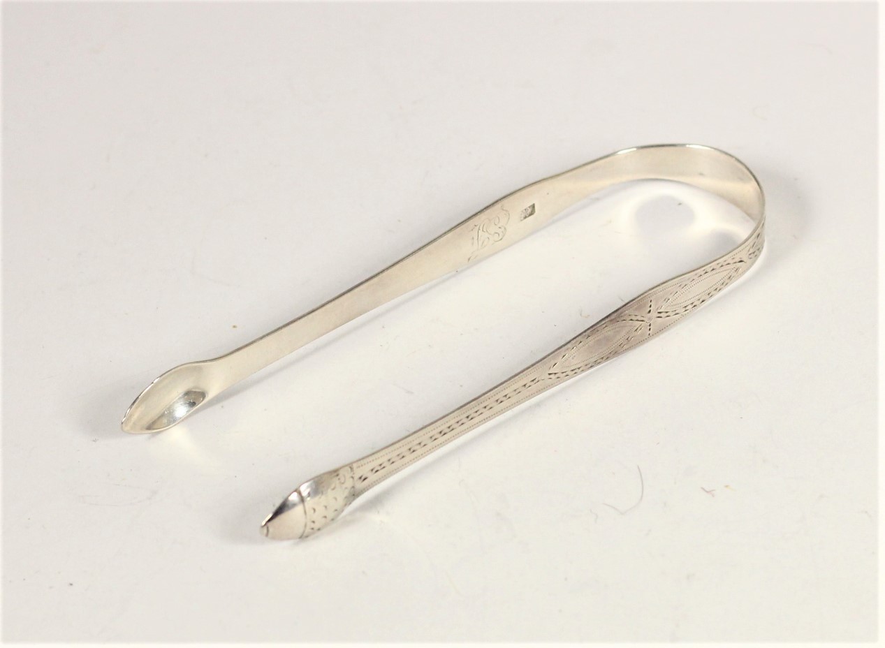 A George III silver pair of bright cut sugar tongs, by Hester Bateman, London 1784, acorn