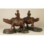A Chinese carved hard wood pair of figures, farmers seated upon water buffalo, raised on ebony bases