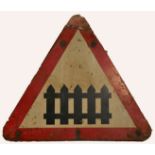 A metal triangular road sign, indicating railway crossing gate ahead