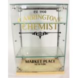 A shop counter glass display cabinet, bearing the name 'Carringtons Chemist Est 1930 Market Place