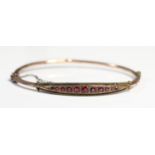 An Edwardian 9ct rose gold and garnet bangle, Chester, date letter worn, as found, internal 6 x 5cm,