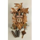 A mid Century Swiss musical cuckoo clock with carved wood decoration, leaf shaped pendulum and three