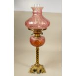 A brass oil lamp with Cranberry fluted shade & reservoir on cast barley twist column, 67cm.