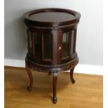 A hardwood circular drinks cabinet, hinged glazed doors, removable tray, carved decoration, cabriole