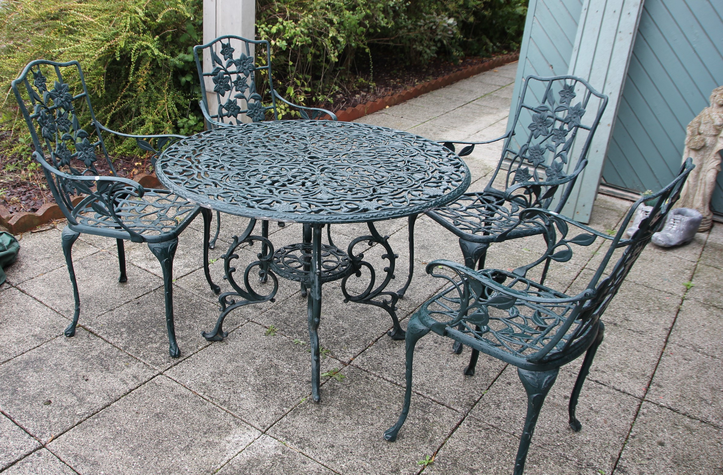 A cast metal garden dining set, painted dark green with floral decoration, with four