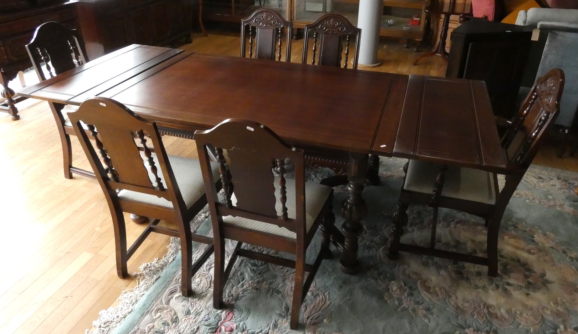 A Jacobean style oak draw leaf dining table raised on turned uprights supported by carved