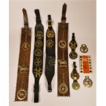 A collection of nineteen authentic horse brasses, attached to leather belts
