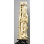 A Chinese ivory figure of a wise man, holding a staff with a bat above him, raised on a hardwood