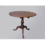 A George III mahogany circular tip top table, raised on a turned pedestal tripod base, diameter 87cm