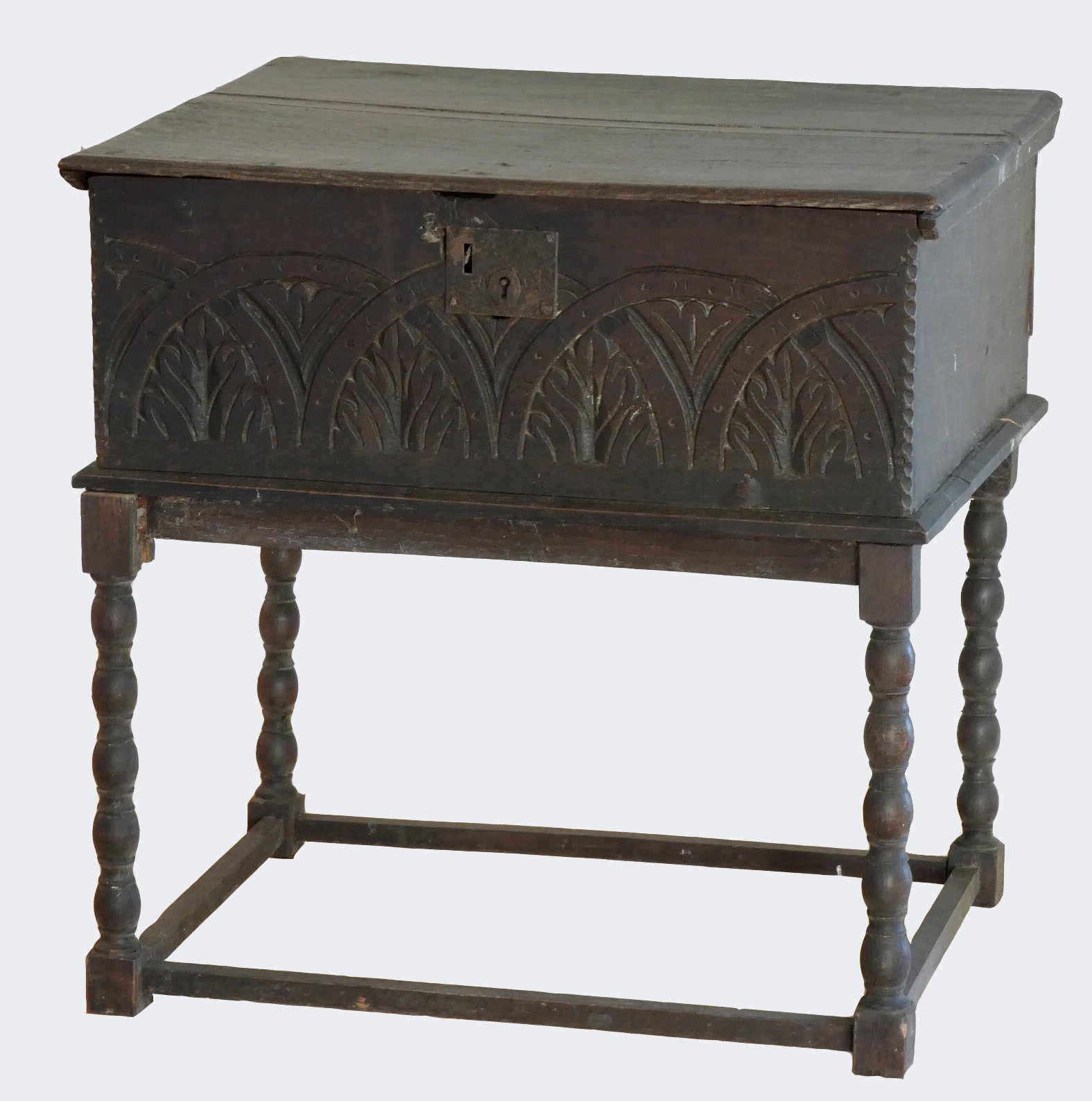 An 18th century and later oak bible box with carved front panel, raised on a later bobbin stand.