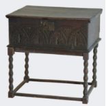 An 18th century and later oak bible box with carved front panel, raised on a later bobbin stand.