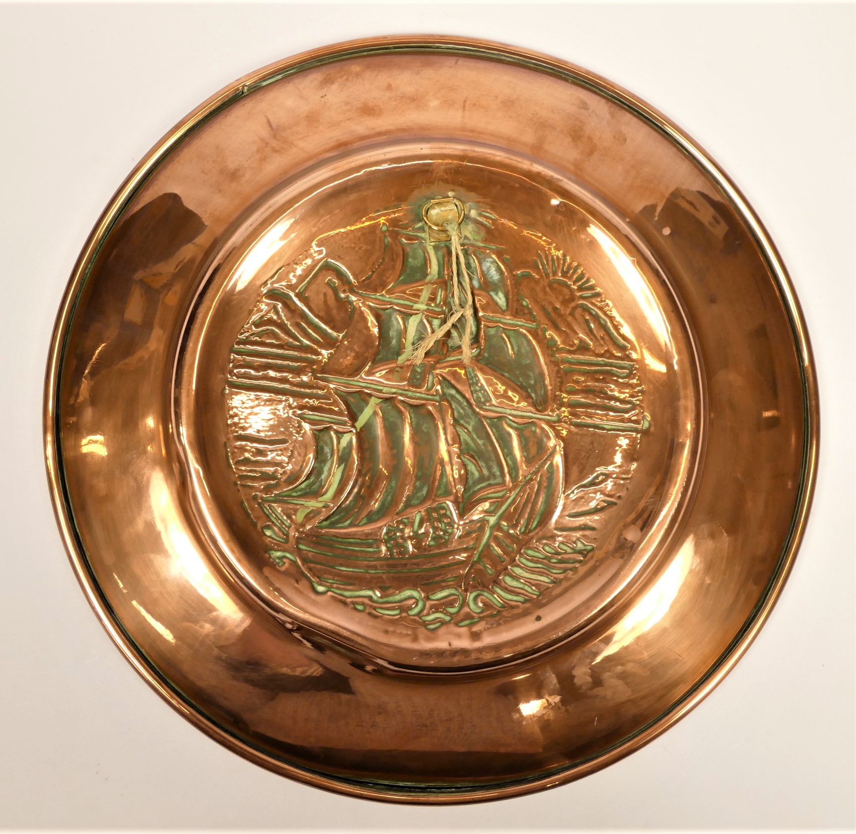 Newlyn School, an Arts and Crafts embossed copper charger, decorated with a galleon, plain fold over