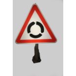 A triangular illuminated road sign depicting a roundabout approaching, 100 x 69 cm