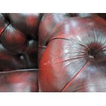 A traditional oxblood red leather three seater chesterfield settee