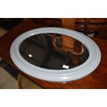 A modern moulded plastic oval wall mirror, in grey, approx. 74cm x 54cm , currently strung in