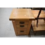 A modern golden oak bedside chest