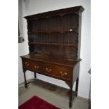 A traditional dark oak dresser having open base, two deep drawers and boarded plate rack