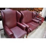 A modern three piece wing back lounge suite , in wine red leather