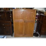 An Arts and Crafts style golden oak compactum style wardrobe, having carved heart motifs to doors,