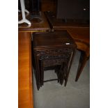 An Oriental hardwood nest of four tables, each having carved frieze depicting birds in foliage